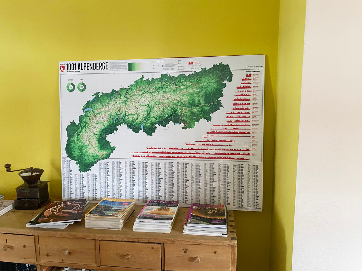 Alpenkarte 1001 Berge – an eine gelbgrüne Wand gelehnt auf einer Kommode